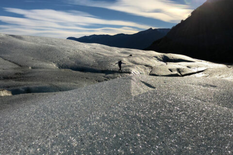 Die Eiswelt Patagoniens. Im Hintergrund sieht man eine Person über die Eismassen der Patagonischen Eisfelder gehen.